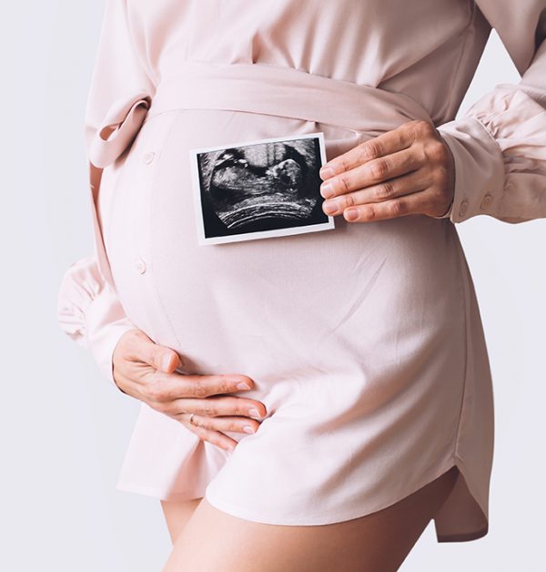 Pregnant woman holding ultrasound baby image.